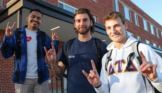 fraternity students pose for a photo outside their dorm